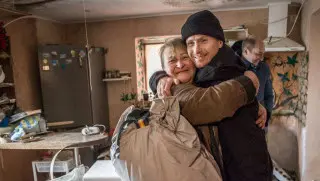 A joyful reunion between two people in a home, showcasing warmth and support in a communal setting.
