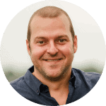 Smiling man with short hair in a blue shirt, representing a professional profile in the context of decentralised technology and compliance.